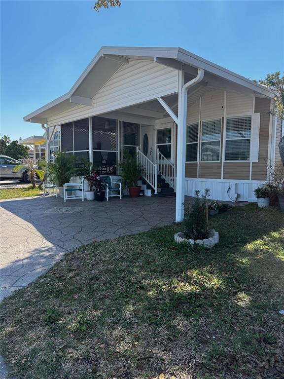 A single-story manufactured home with a screened-in porch, carport, and a patterned concrete driveway — 123 PANSY STREET, DAVENPORT, FL