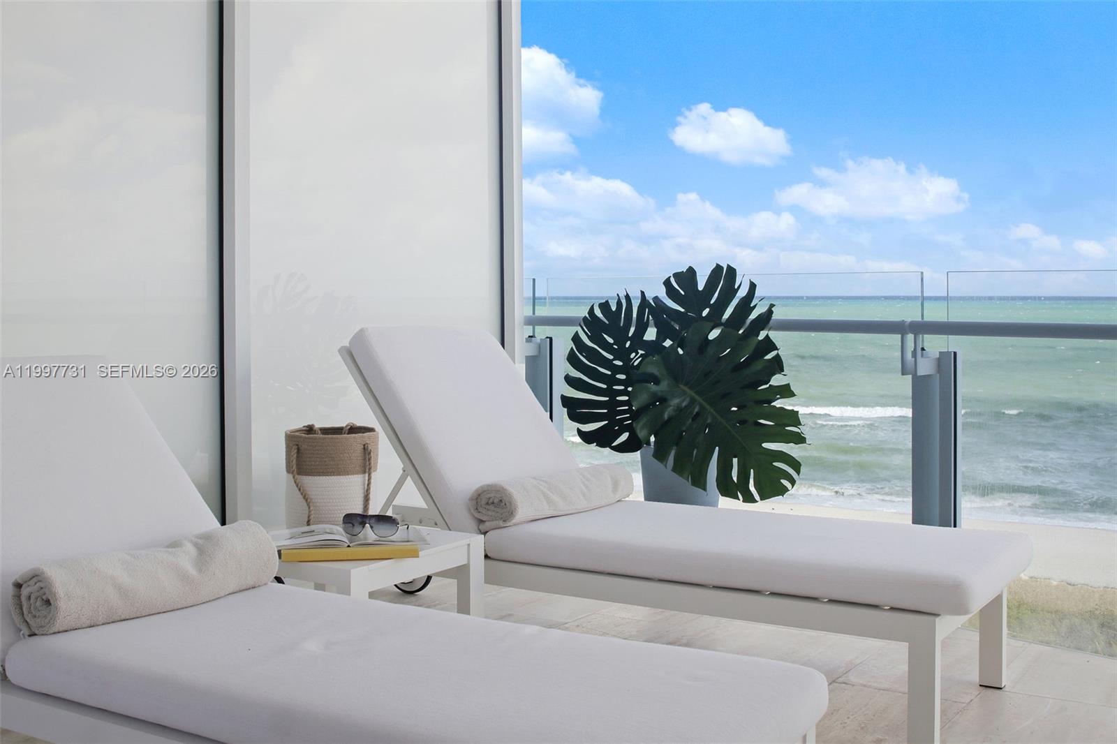 Two white lounge chairs sit on a balcony overlooking the ocean with a potted plant — 9001 Collins Ave # 605, Surfside FL 33154, SURFSIDE, FL
