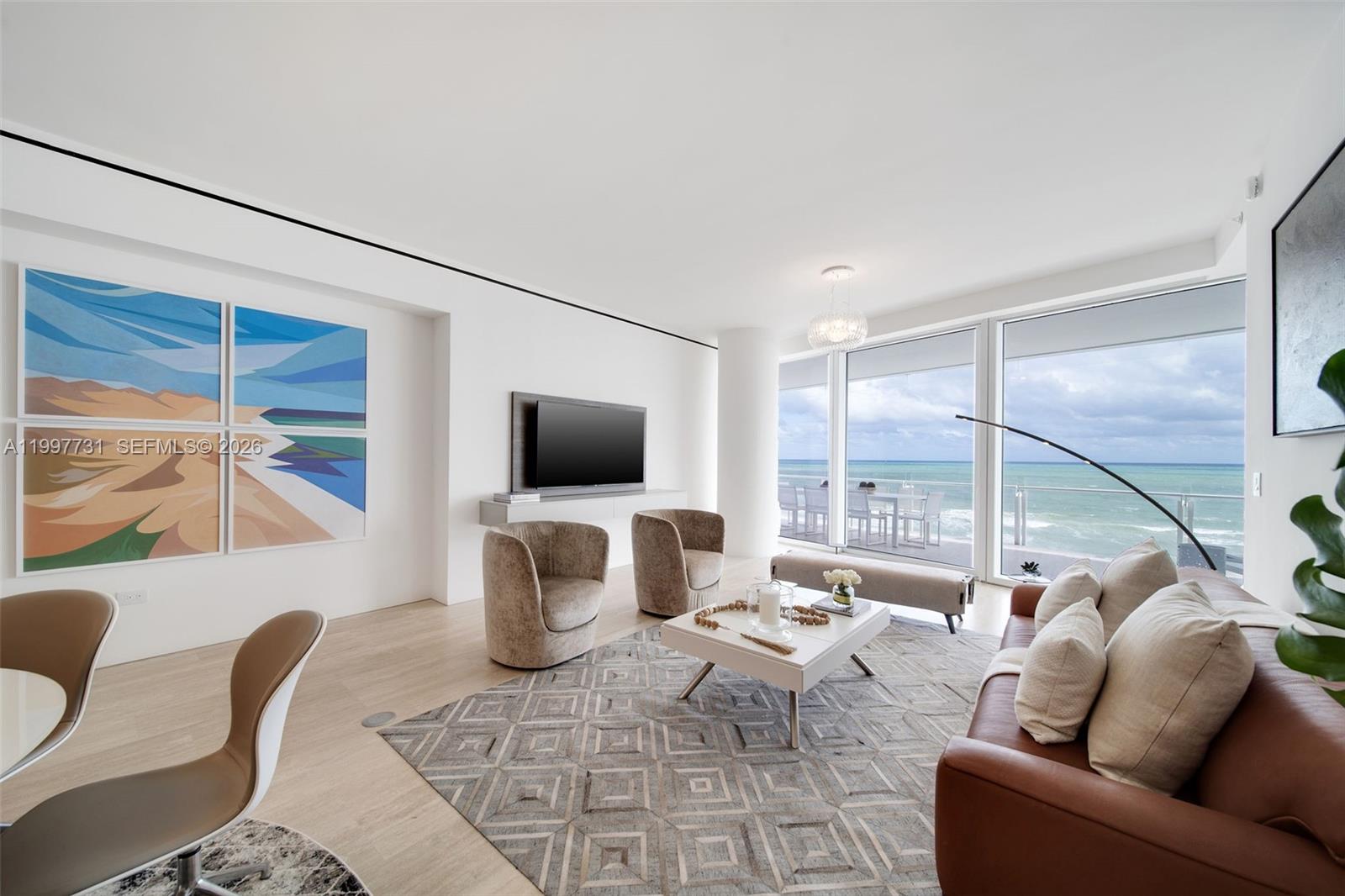 A modern living room features a brown sofa, two armchairs, and floor-to-ceiling ocean view windows — 9001 Collins Ave # 605, Surfside FL 33154, SURFSIDE, FL