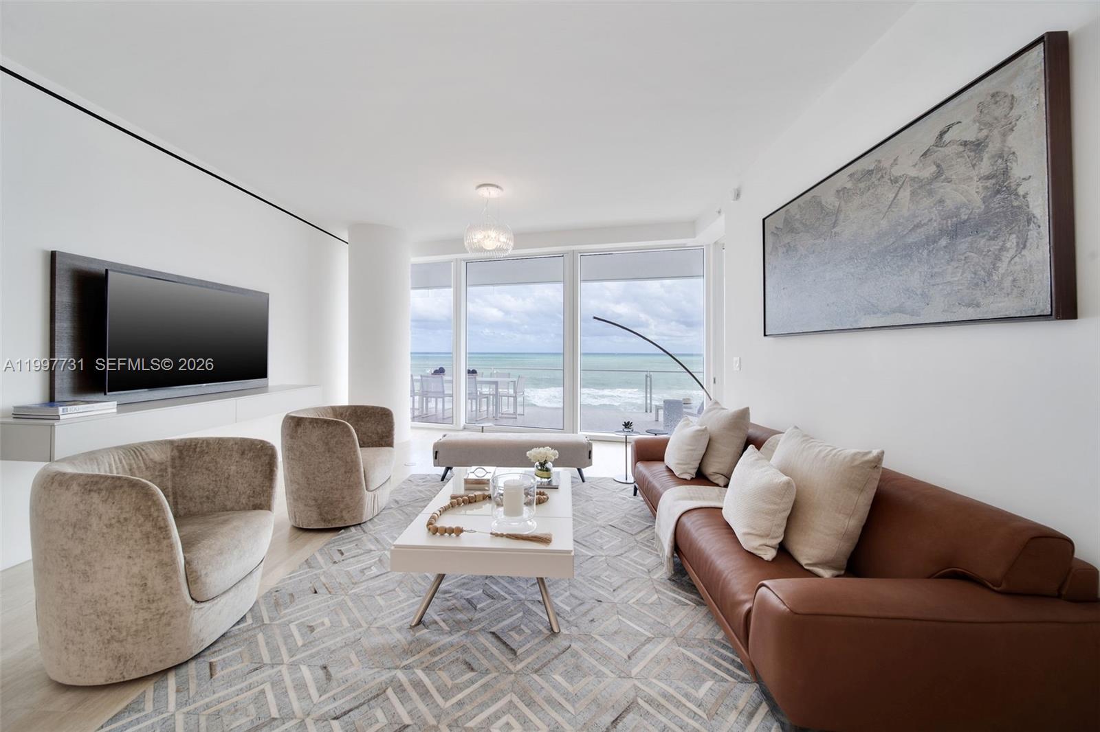 A modern living room features a brown leather sofa, two armchairs, and ocean views — 9001 Collins Ave # 605, Surfside FL 33154, SURFSIDE, FL
