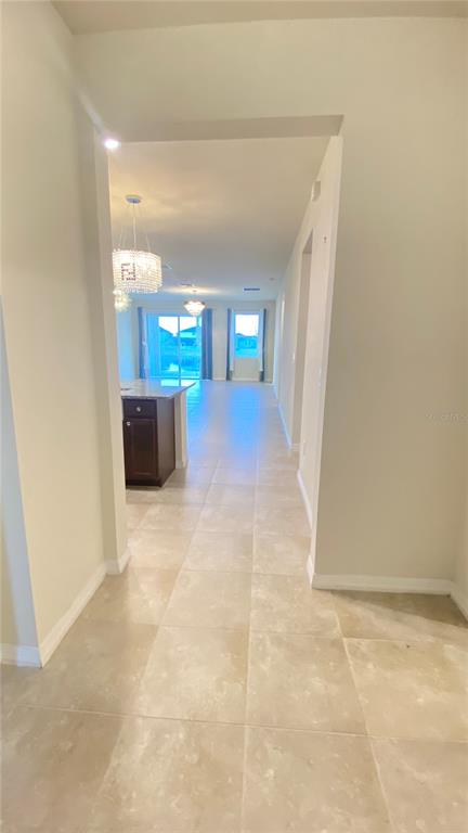 A view from a hallway looking toward a kitchen with dark cabinets and tile flooring — 13515 PALMERA VISTA DRIVE, RIVERVIEW, FL