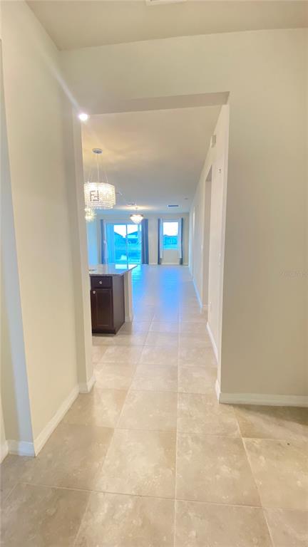 A view from a hallway looking into an open-concept kitchen and living area with tile floors — 13515 PALMERA VISTA DRIVE, RIVERVIEW, FL