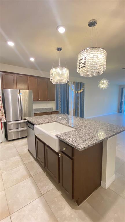 A kitchen features a granite-topped island with a farmhouse sink and two crystal pendant lights — 13515 PALMERA VISTA DRIVE, RIVERVIEW, FL