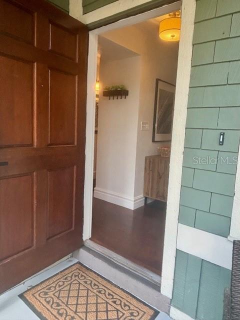 An open wooden front door reveals an interior entryway with hardwood floors and a light fixture — 5319 SW 88TH COURT, GAINESVILLE, FL