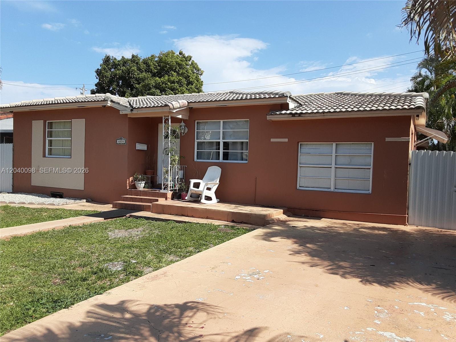 A single-story house with a terracotta-colored exterior, a tiled roof, and a concrete driveway — 4074 NW 4th St, Miami FL 33126, MIAMI, FL