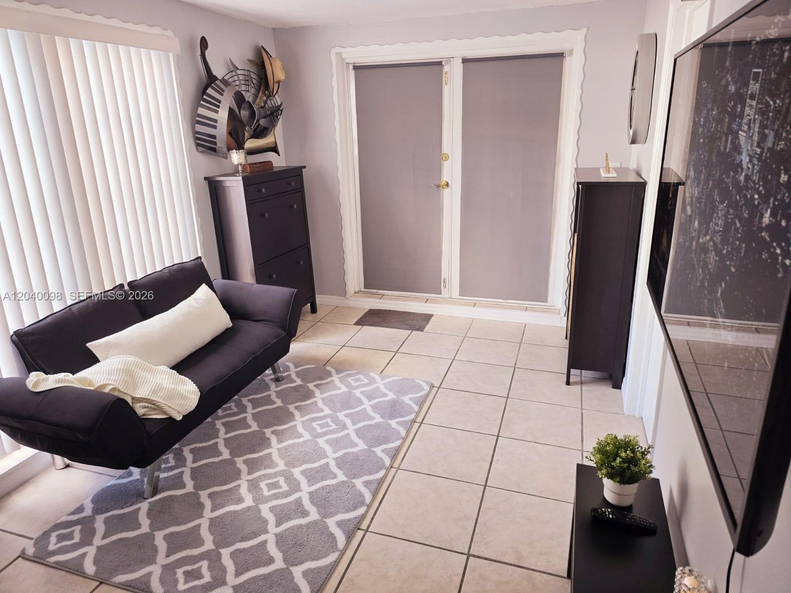 A small living room features a black sofa, a patterned rug, and tiled flooring — 4074 NW 4th St, Miami FL 33126, MIAMI, FL