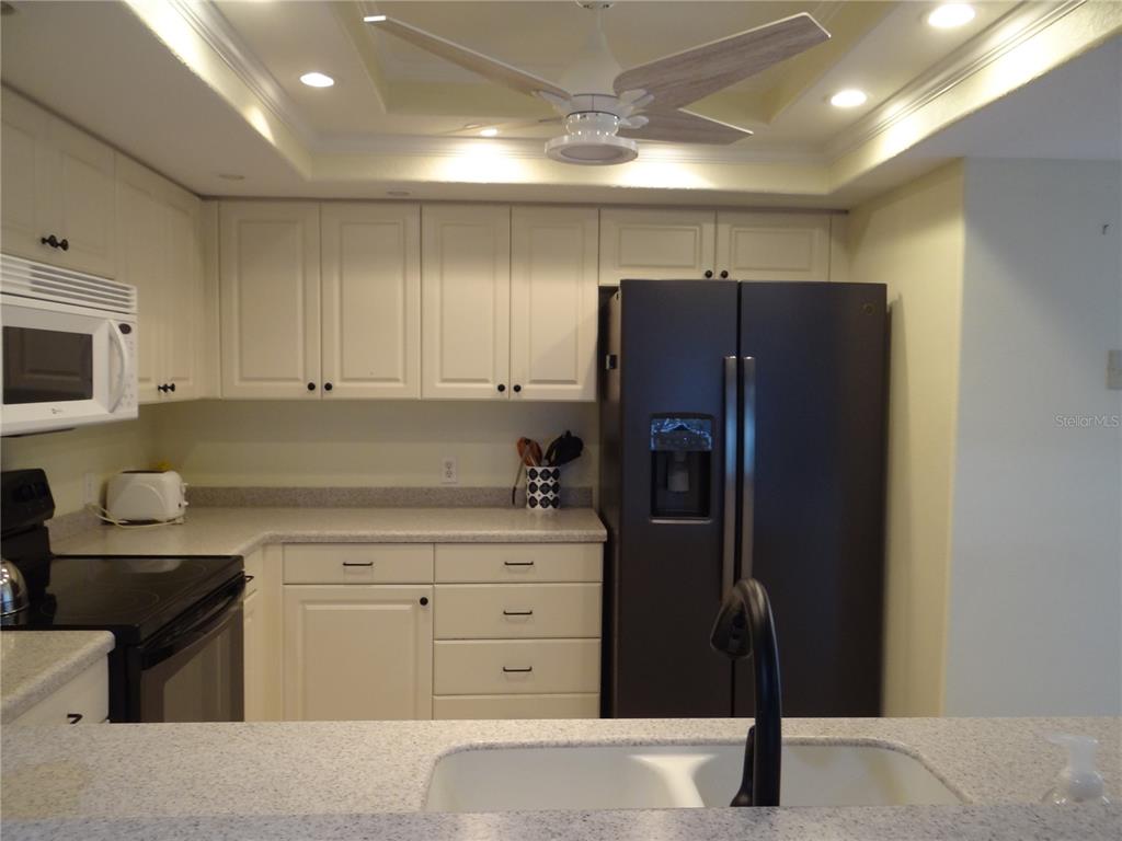 A kitchen features white cabinets, a black refrigerator, a black stove, and a speckled countertop — 601 SHREVE STREET UNIT 41C, PUNTA GORDA, FL