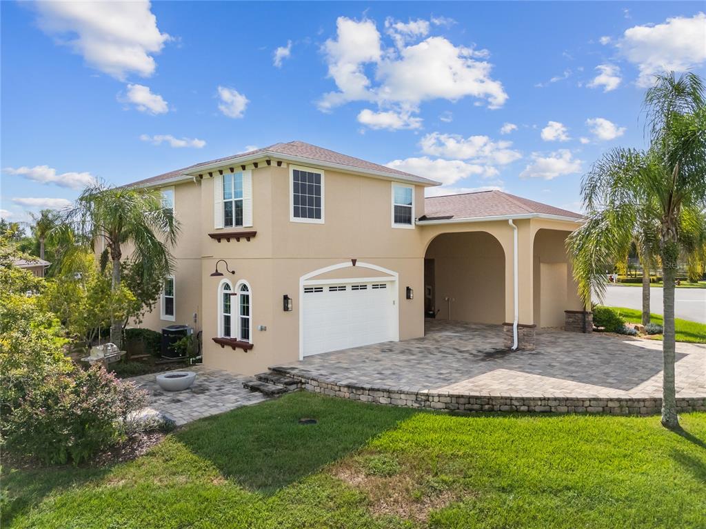 A two-story tan house features a white garage, a paved driveway, and a covered carport — 398 NOLANE LANE, POLK CITY, FL