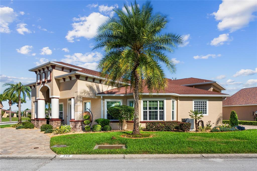 A single-story stucco house with a palm tree in the front yard under a blue sky — 398 NOLANE LANE, POLK CITY, FL