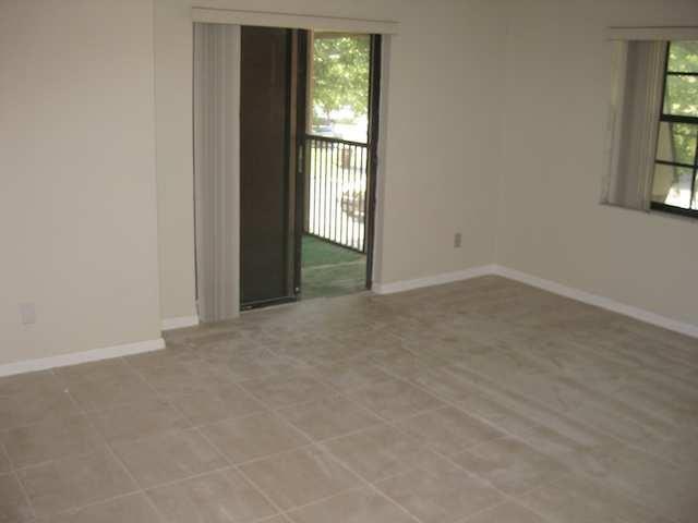 An empty room with light-colored tile flooring, a sliding glass door, and a window — 3665 NW 94th Avenue # 3j, Sunrise FL 33351, SUNRISE, FL