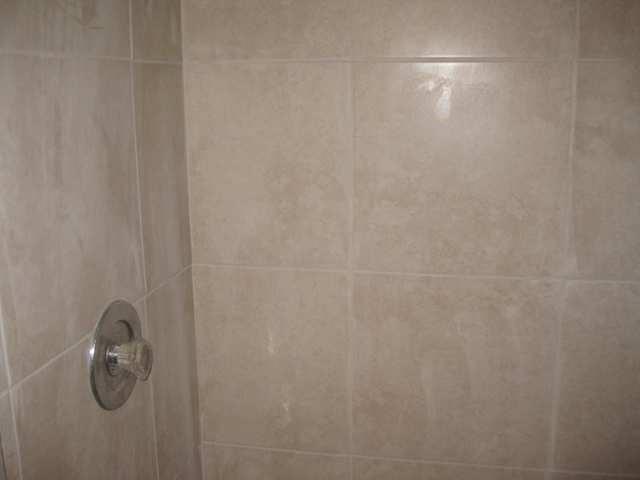 A close-up view of a shower wall featuring beige square tiles and a metal handle — 3665 NW 94th Avenue # 3j, Sunrise FL 33351, SUNRISE, FL