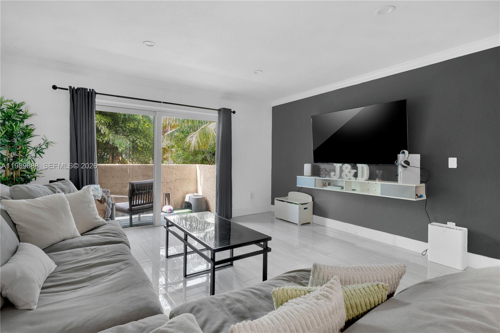 A living room features a gray accent wall with a mounted television and sliding glass doors — 9956 SW 88th St # 1, Miami FL 33176, MIAMI, FL
