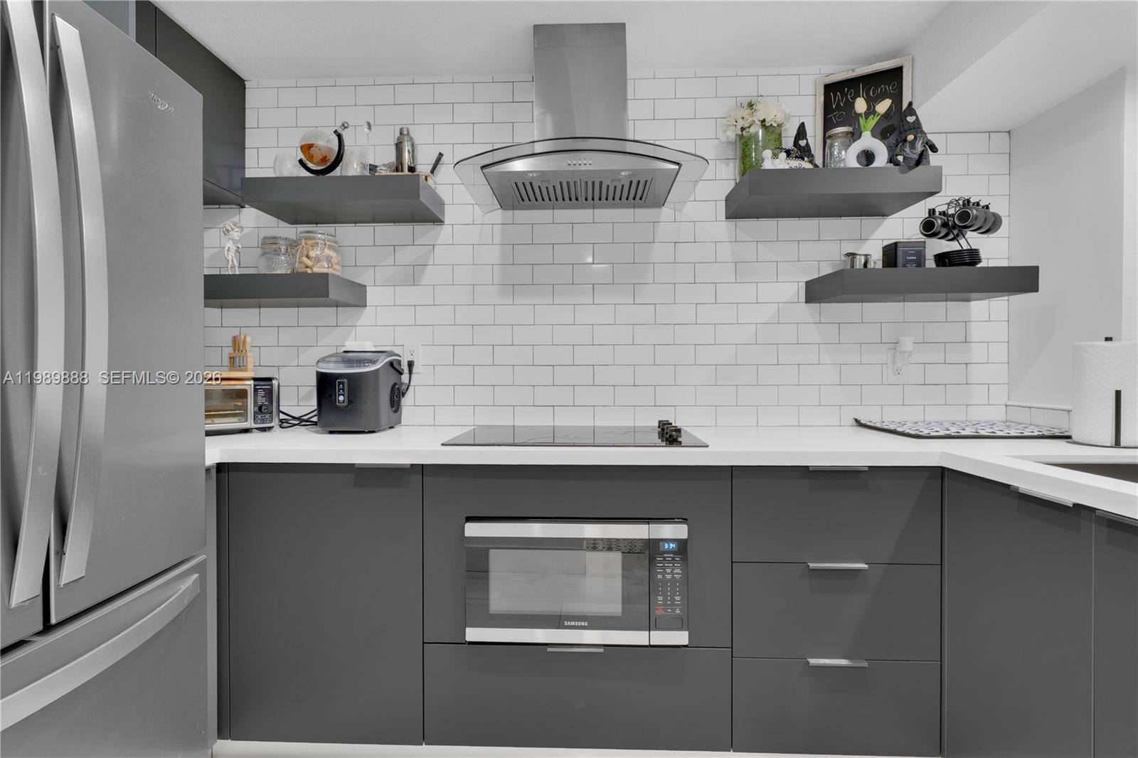 A modern kitchen features dark gray cabinets, white countertops, subway tile backsplash, and floating shelves — 9956 SW 88th St # 1, Miami FL 33176, MIAMI, FL