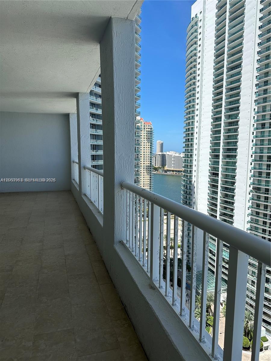 A balcony with light-colored tile flooring overlooks a body of water and high-rise buildings — 170 SE 14th St # 2604, Miami FL 33131, MIAMI, FL