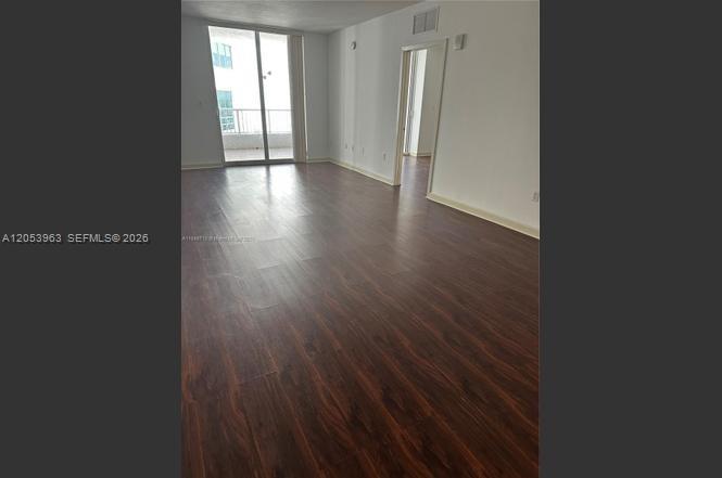 An empty room with dark wood-look flooring and a sliding glass door to a balcony — 170 SE 14th St # 2604, Miami FL 33131, MIAMI, FL