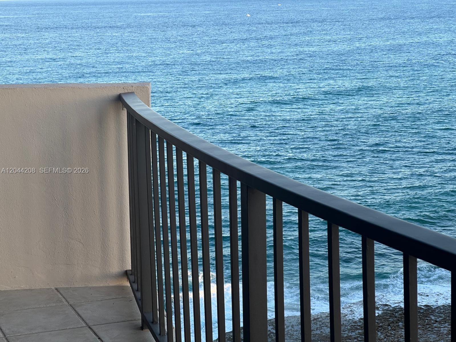 A balcony with a dark metal railing overlooks the ocean — 4200 N Ocean Dr # 1103, Riviera Beach FL 33404, RIVIERA BEACH, FL