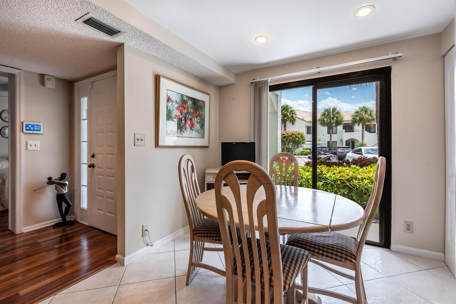 A dining area with a round wooden table, four chairs, and a sliding glass door — 15831 Loch Maree Lane # 5502, Delray Beach FL 33446, DELRAY BEACH, FL