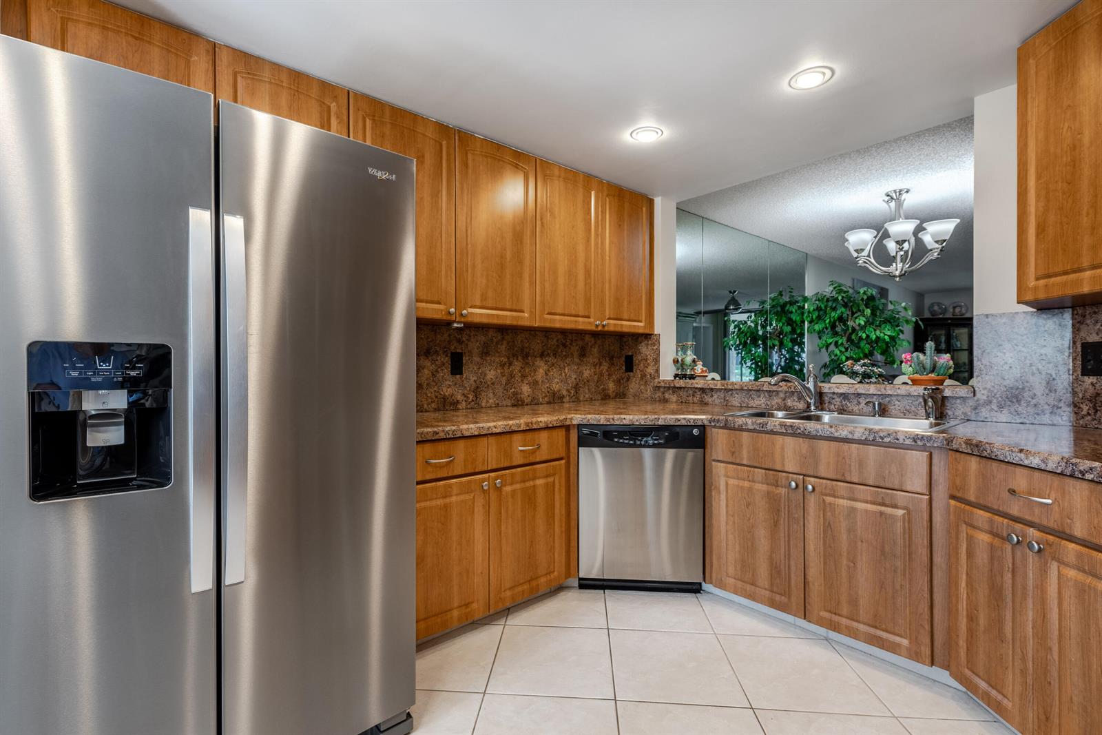 A kitchen features stainless steel appliances, wood cabinets, and granite countertops with tile flooring — 15831 Loch Maree Lane # 5502, Delray Beach FL 33446, DELRAY BEACH, FL