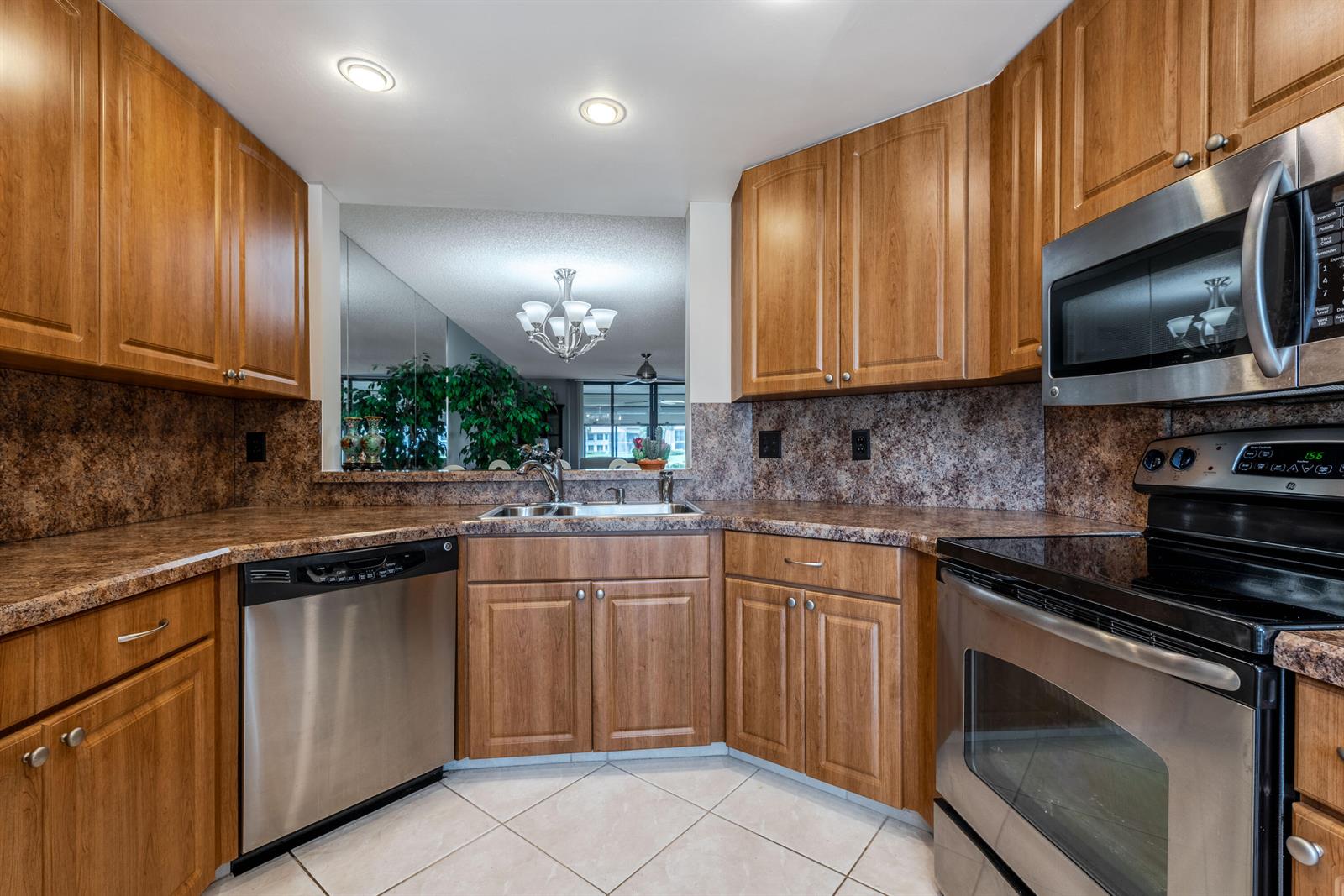 A kitchen features wood cabinets, stainless steel appliances, and a pass-through window to another room — 15831 Loch Maree Lane # 5502, Delray Beach FL 33446, DELRAY BEACH, FL