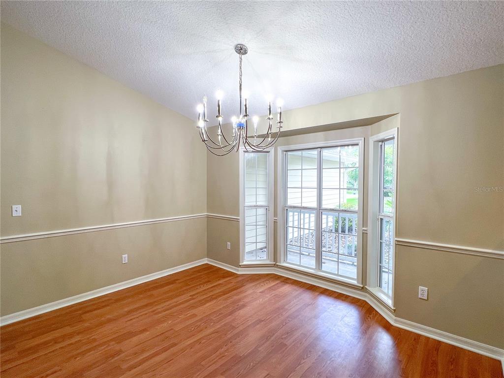 A dining room with wood flooring, beige walls, a chair rail, and a chandelier — 8414 SW 66TH LANE, GAINESVILLE, FL