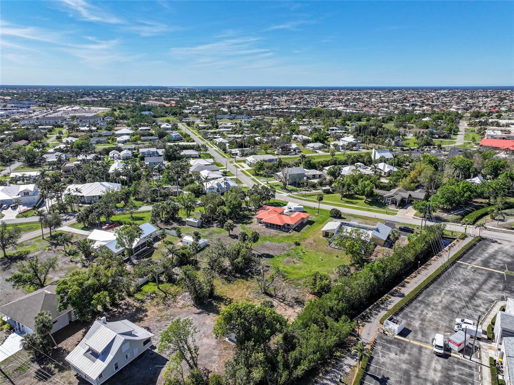 An aerial view shows a residential neighborhood with houses, trees, and a paved parking lot — 509 GILL STREET, PUNTA GORDA, FL