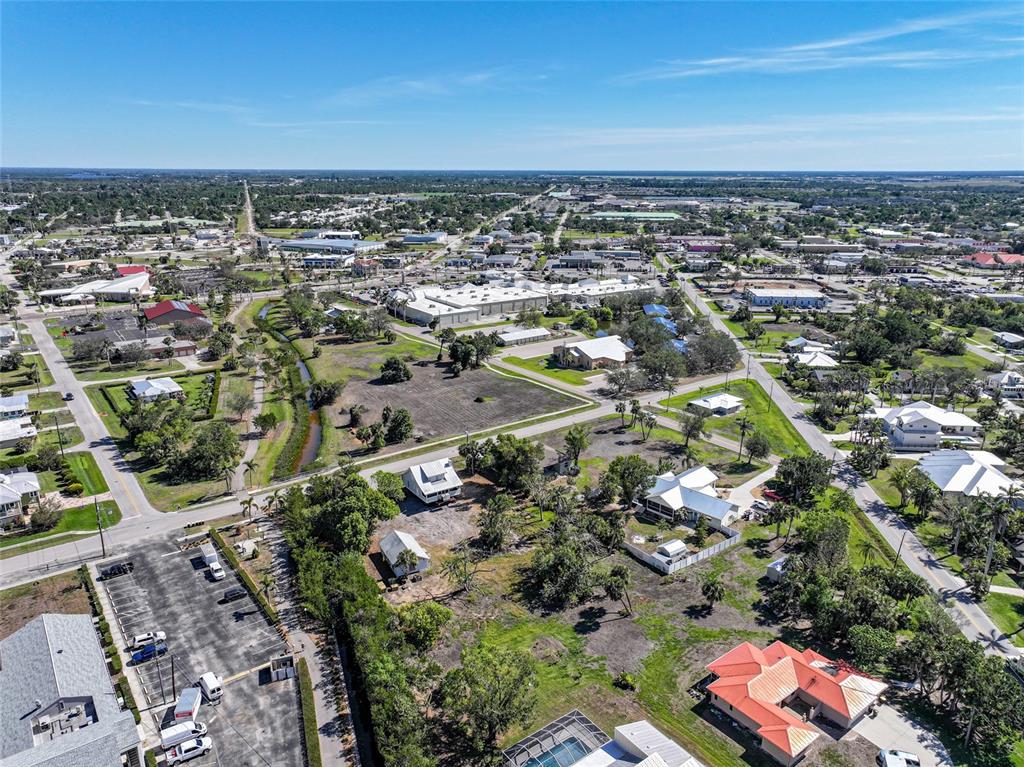 An aerial view shows a suburban neighborhood with houses, parking lots, and undeveloped land — 509 GILL STREET, PUNTA GORDA, FL