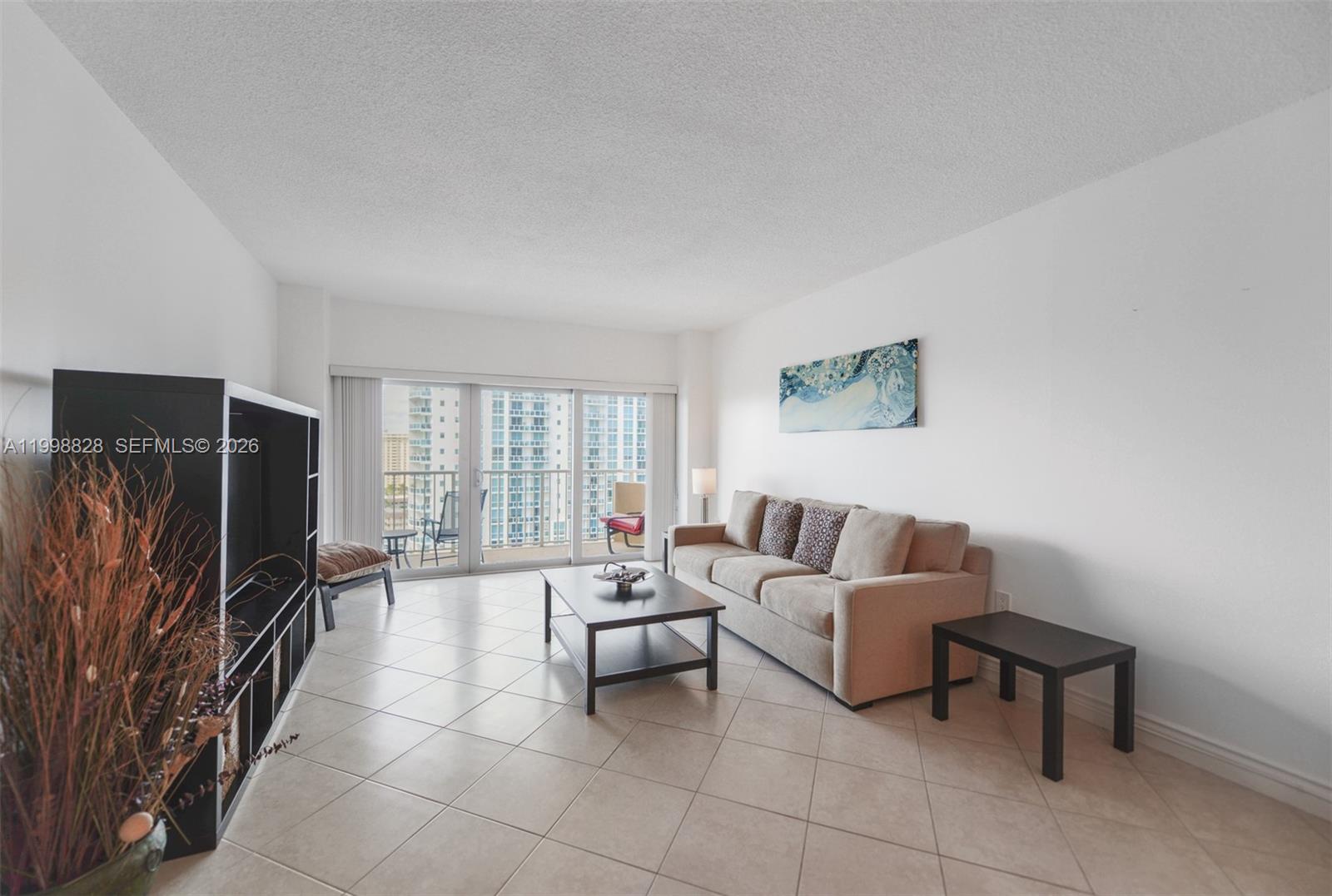 A living room features a beige sofa, a dark coffee table, and a balcony view — 1965 S Ocean Dr # 14D, Hallandale Beach FL 33009, HALLANDALE BEACH, FL
