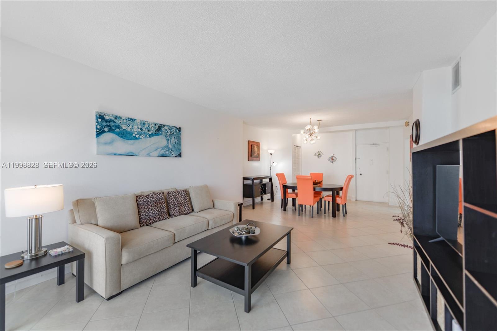 A living and dining area features a beige sofa, dark furniture, and orange dining chairs — 1965 S Ocean Dr # 14D, Hallandale Beach FL 33009, HALLANDALE BEACH, FL