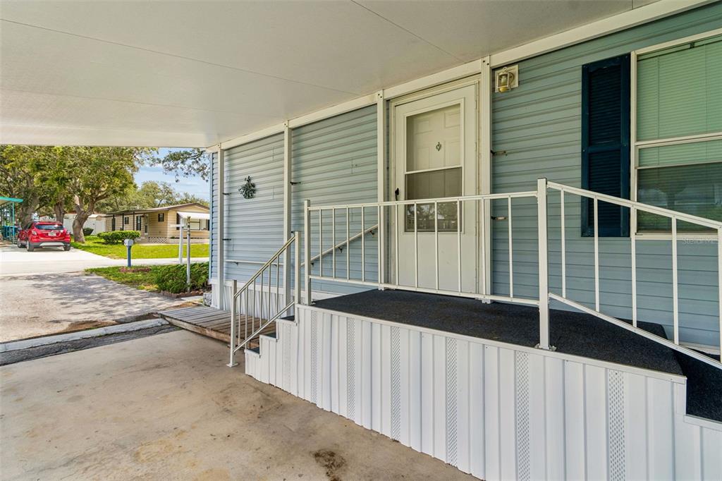 A light blue mobile home exterior features a covered carport, concrete steps, and metal railings — 34992 FRASER STREET, DADE CITY, FL