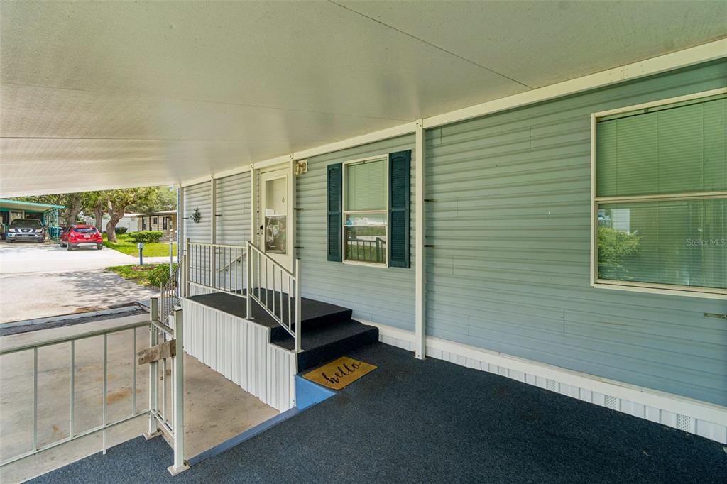 A covered carport leads to a set of stairs with a railing and a front door — 34992 FRASER STREET, DADE CITY, FL