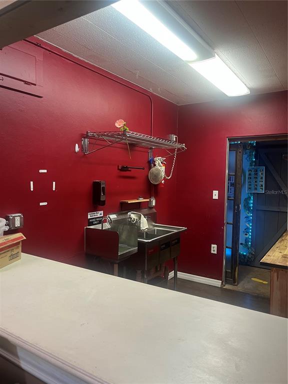 A commercial kitchen area features a stainless steel sink, red walls, and overhead lighting — 334 N DONNELLY STREET, MOUNT DORA, FL