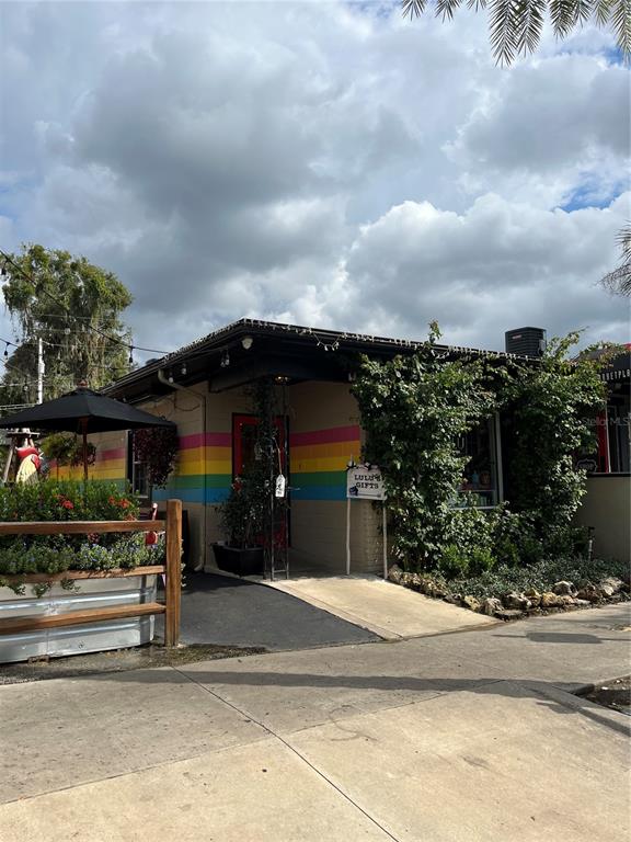 A small building with a rainbow-striped exterior wall, a black umbrella, and lush greenery — 334 N DONNELLY STREET, MOUNT DORA, FL