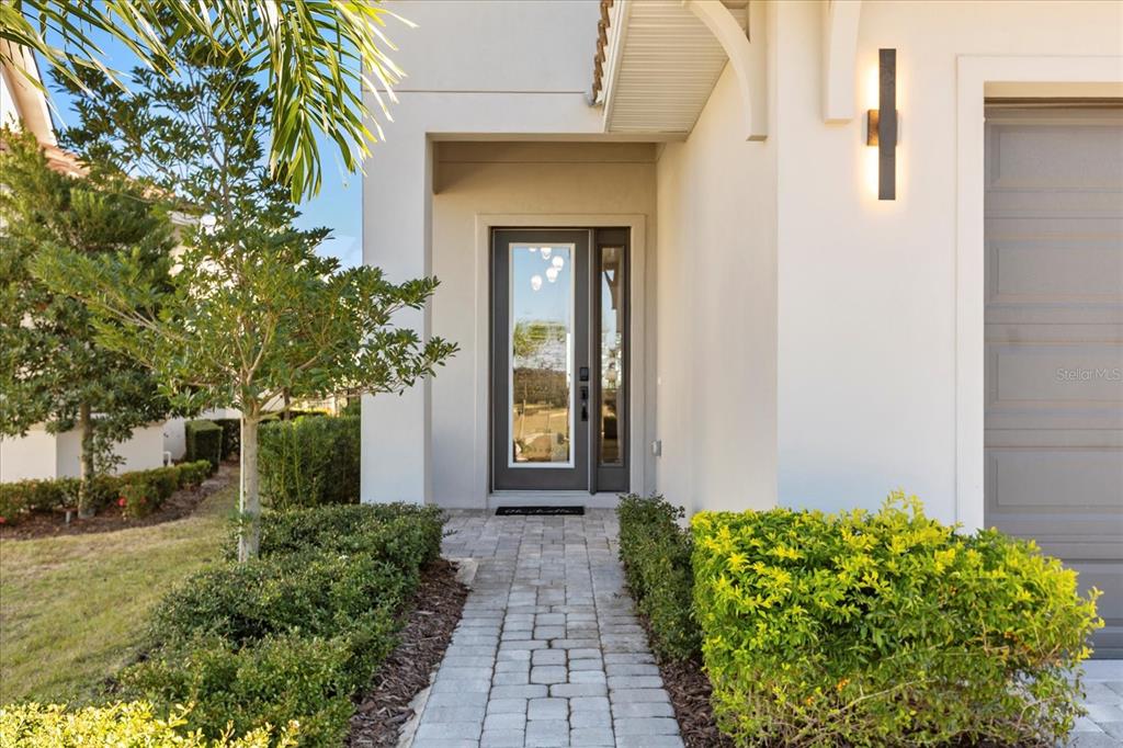 A paved walkway leads to the front entrance of a modern home with a garage — 16254 RAVENNA COURT, MONTVERDE, FL