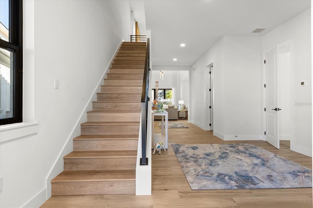 A staircase with light wood treads and a black railing stands in a white entryway — 16254 RAVENNA COURT, MONTVERDE, FL