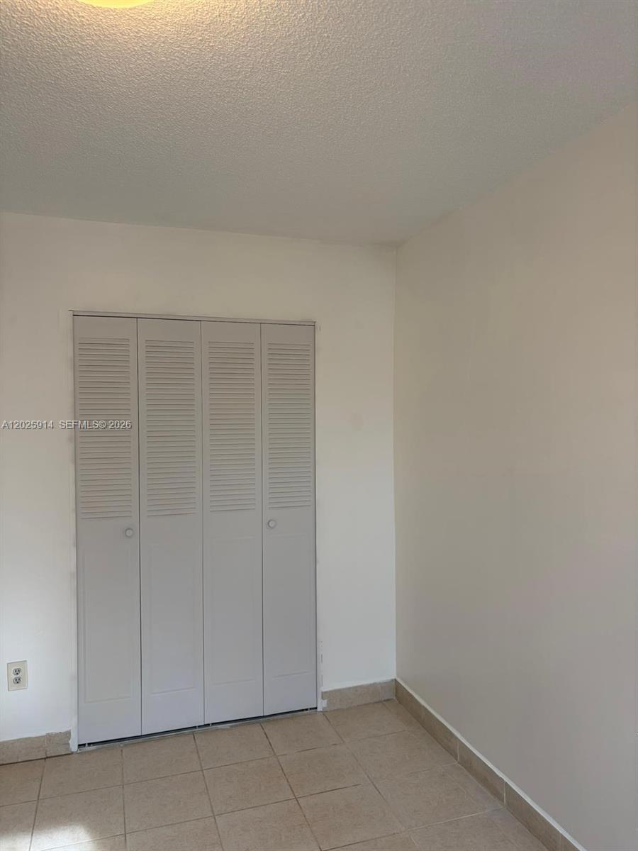 A room with beige tile flooring, white walls, and a four-panel louvered closet door — 6820 W Flagler St # 212, Miami FL 33144, MIAMI, FL