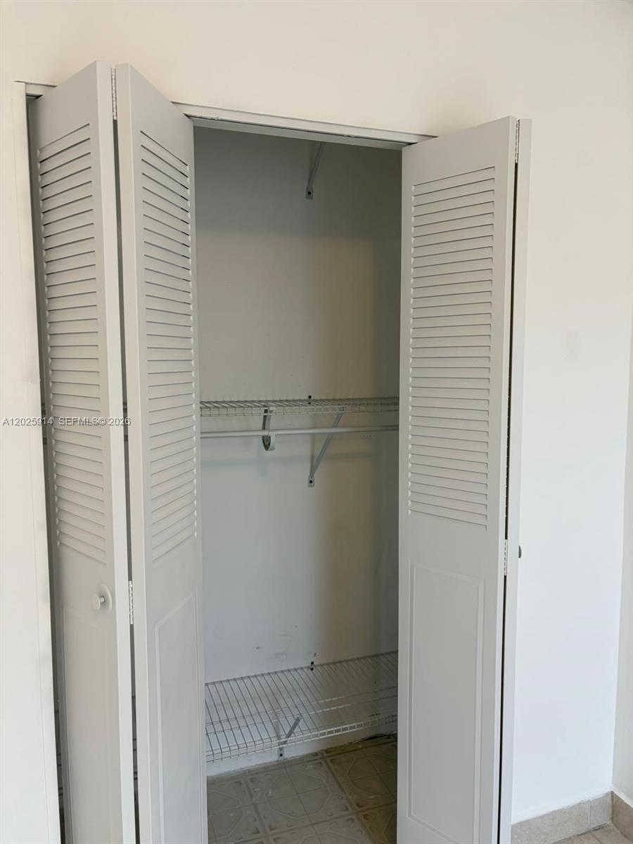 A white louvered bifold closet door stands open, revealing wire shelving inside — 6820 W Flagler St # 212, Miami FL 33144, MIAMI, FL