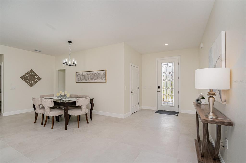 A dining area and entryway feature light tile flooring, neutral walls, and a glass-paneled door — 296 DELAKE ROAD NW, PALM BAY, FL