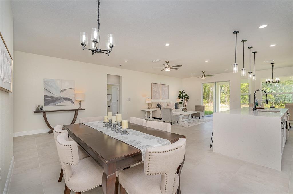 An open-concept dining and living area features tile floors, a kitchen island, and neutral decor — 296 DELAKE ROAD NW, PALM BAY, FL