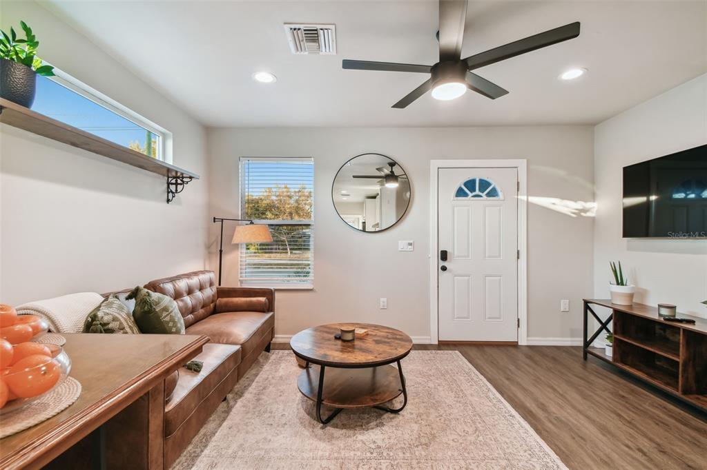 A living room features a brown leather sofa, round coffee table, and a ceiling fan — 2310 30TH AVENUE N, ST PETERSBURG, FL