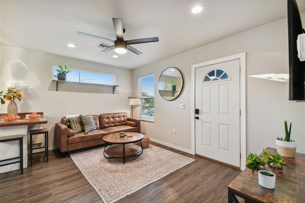 A living room features a brown leather sofa, a round coffee table, and a front door — 2310 30TH AVENUE N, ST PETERSBURG, FL
