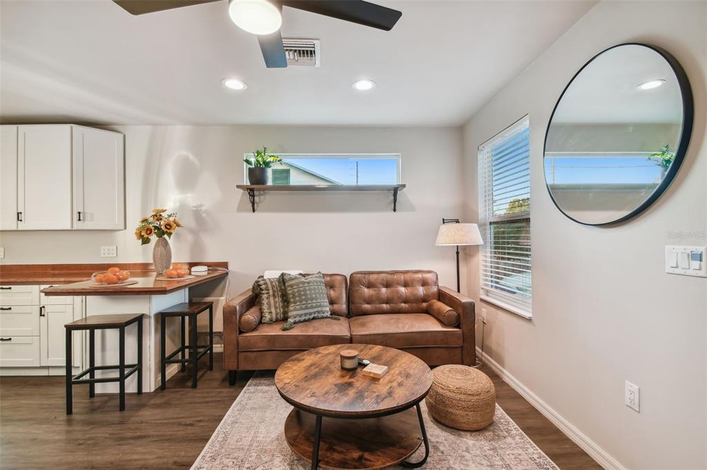 A living room with a brown leather sofa, round coffee table, and kitchen breakfast bar — 2310 30TH AVENUE N, ST PETERSBURG, FL