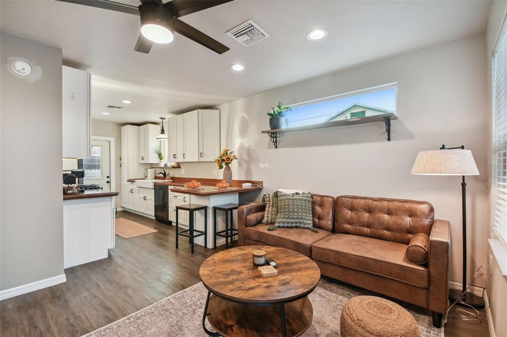A living room with a brown leather sofa and coffee table opens into a white kitchen — 2310 30TH AVENUE N, ST PETERSBURG, FL