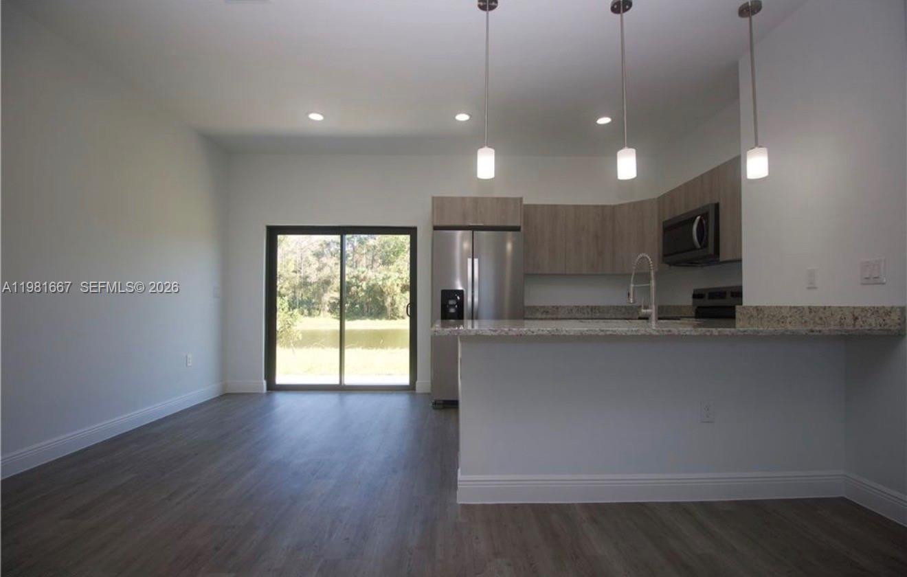 A kitchen with stainless steel appliances and a breakfast bar opens to a living area — 8004 Spice CT, La Belle FL 33935, LA BELLE, FL
