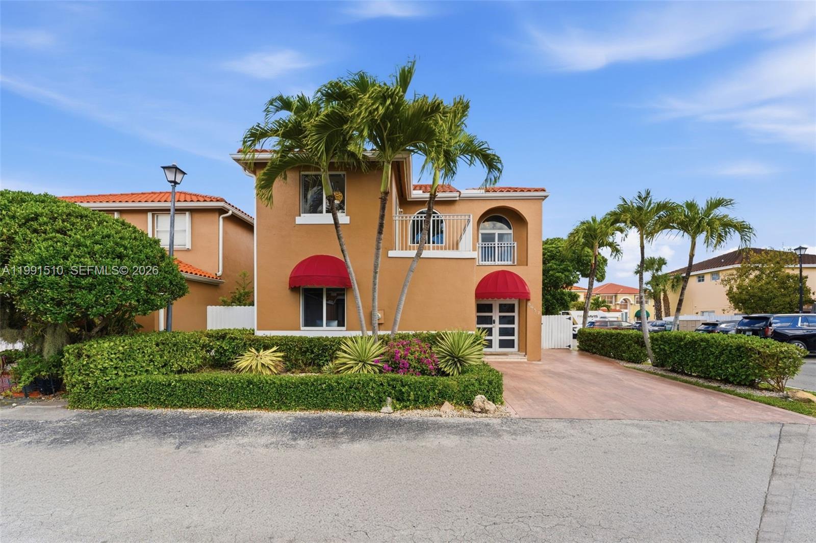 A two-story tan stucco house features red awnings, a balcony, and palm trees — 8657 NW 2nd St, Miami FL 33126, MIAMI, FL