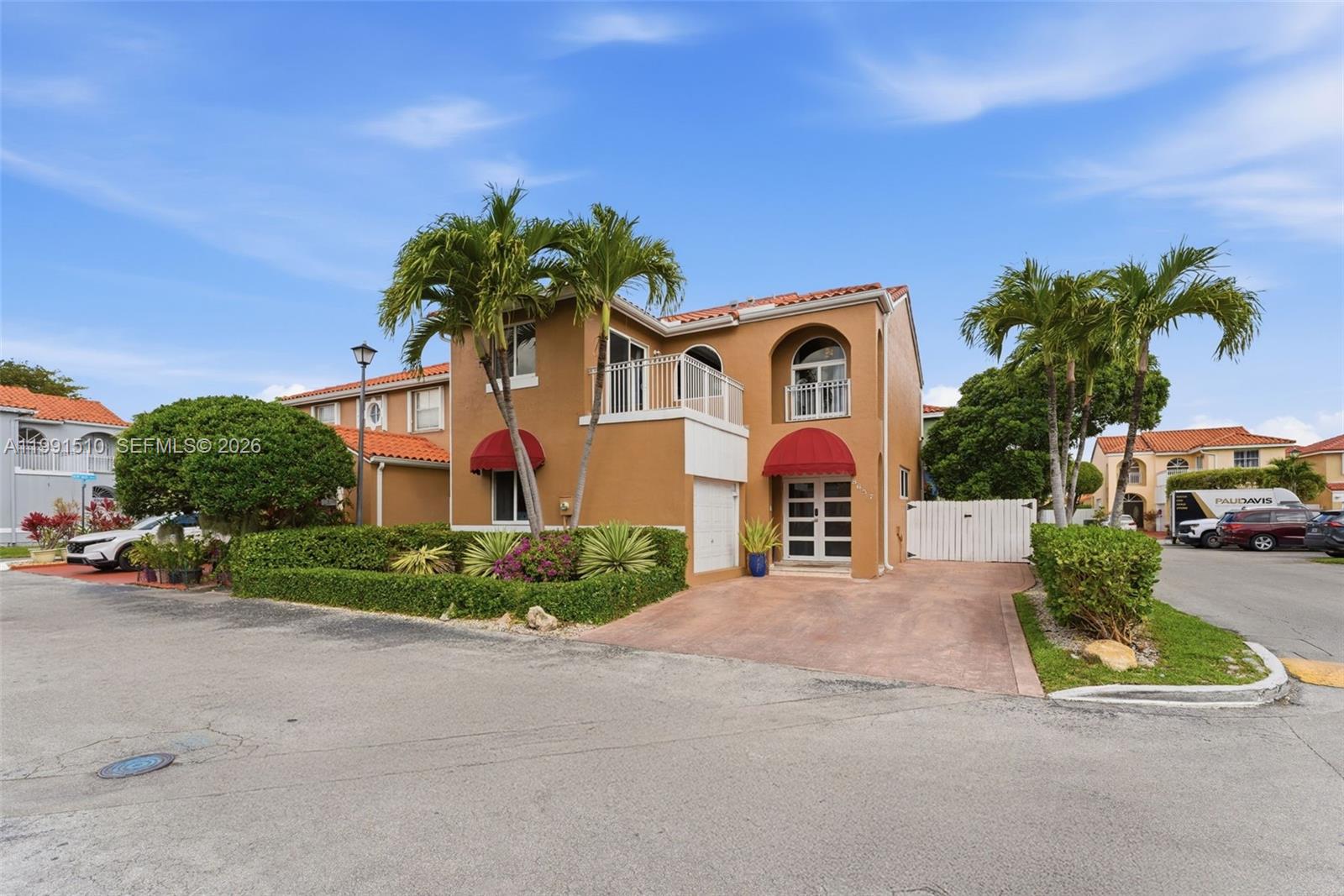 A two-story tan stucco house features a red-tiled roof, red awnings, and a paved driveway — 8657 NW 2nd St, Miami FL 33126, MIAMI, FL