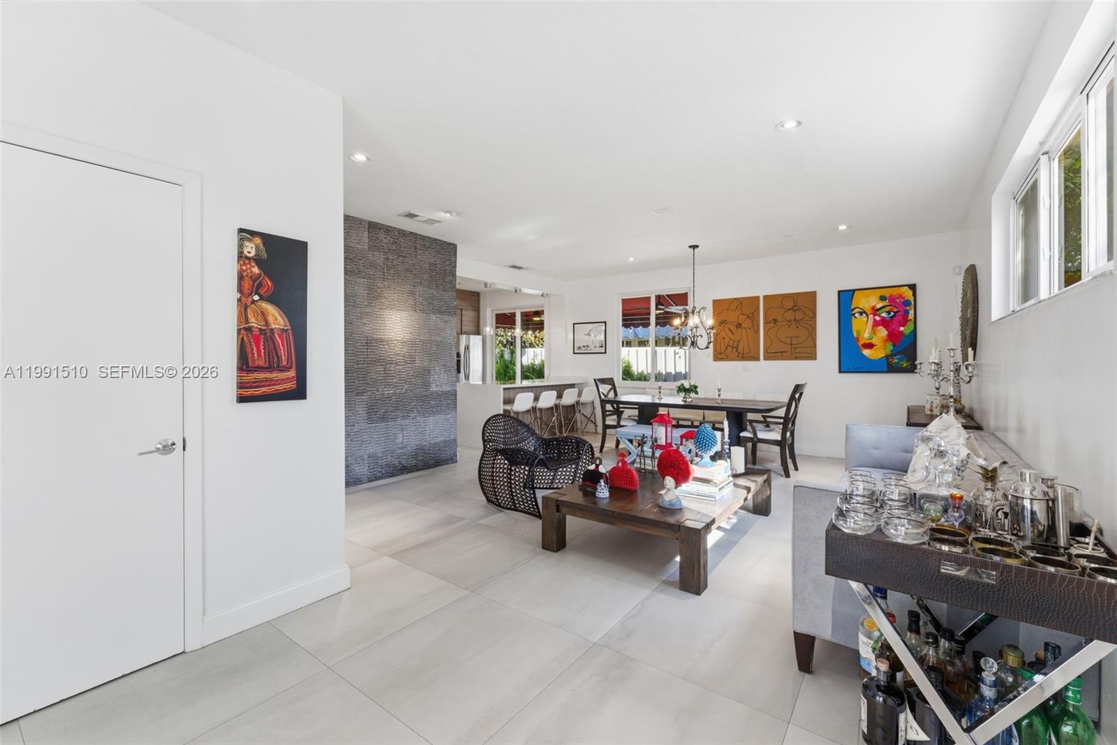 An open-concept living and dining area features tile flooring, a stone accent wall, and artwork — 8657 NW 2nd St, Miami FL 33126, MIAMI, FL