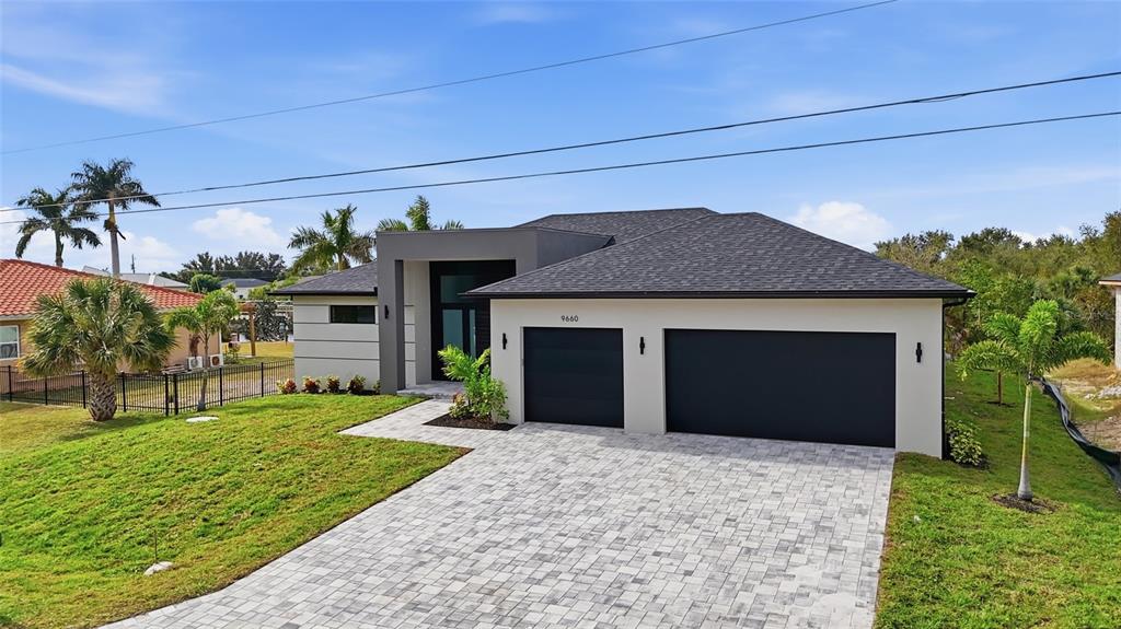 A modern single-story house with a paved driveway, two garage doors, and a flat roof — 9660 PRESIDENT CIRCLE, PORT CHARLOTTE, FL
