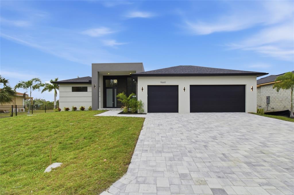 A modern single-story house features a paved driveway, a two-car garage, and a recessed entryway — 9660 PRESIDENT CIRCLE, PORT CHARLOTTE, FL