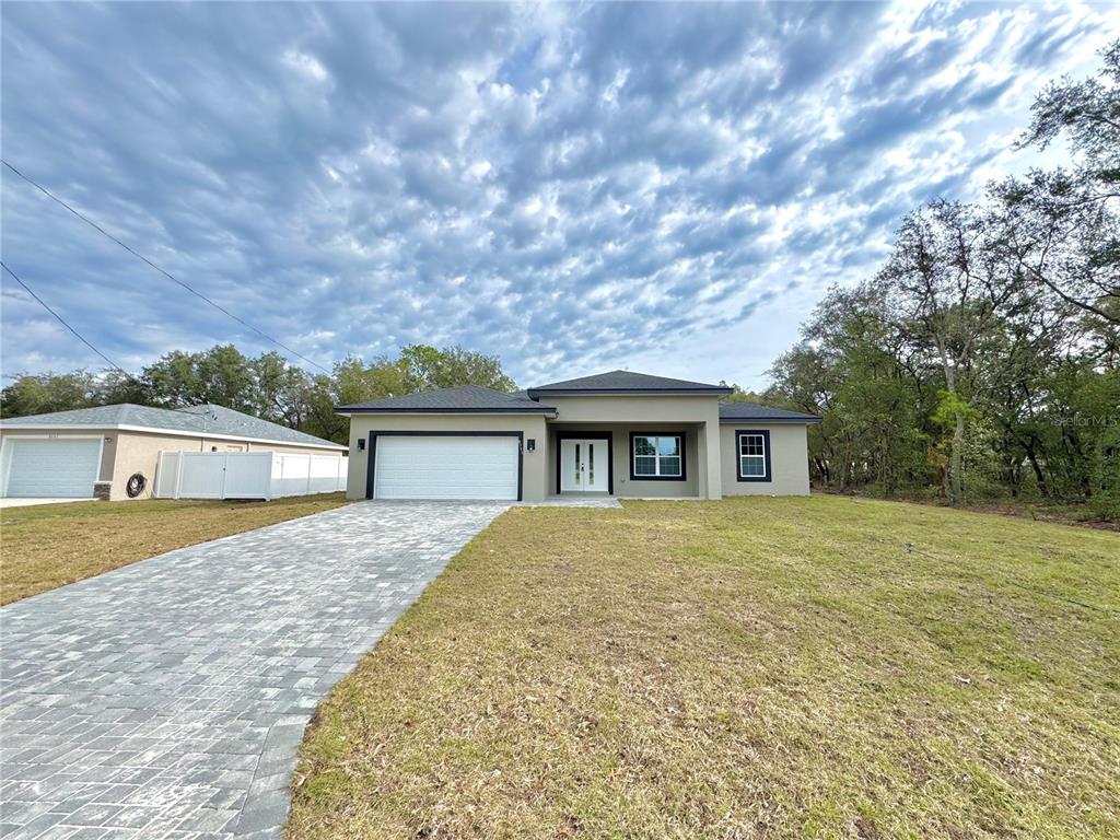 A single-story house with a paved driveway, white garage door, and dark roof — 8593 N MULLER WAY, CITRUS SPRINGS, FL