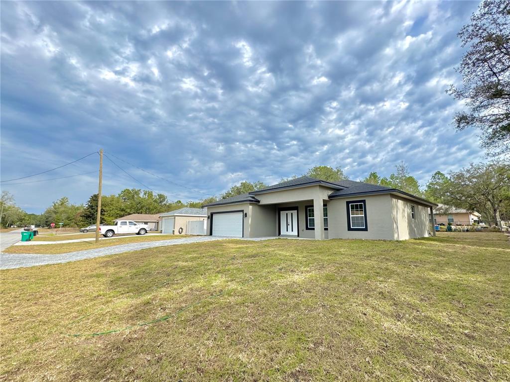 A single-story house with a gray exterior, dark trim, and a paved driveway — 8593 N MULLER WAY, CITRUS SPRINGS, FL